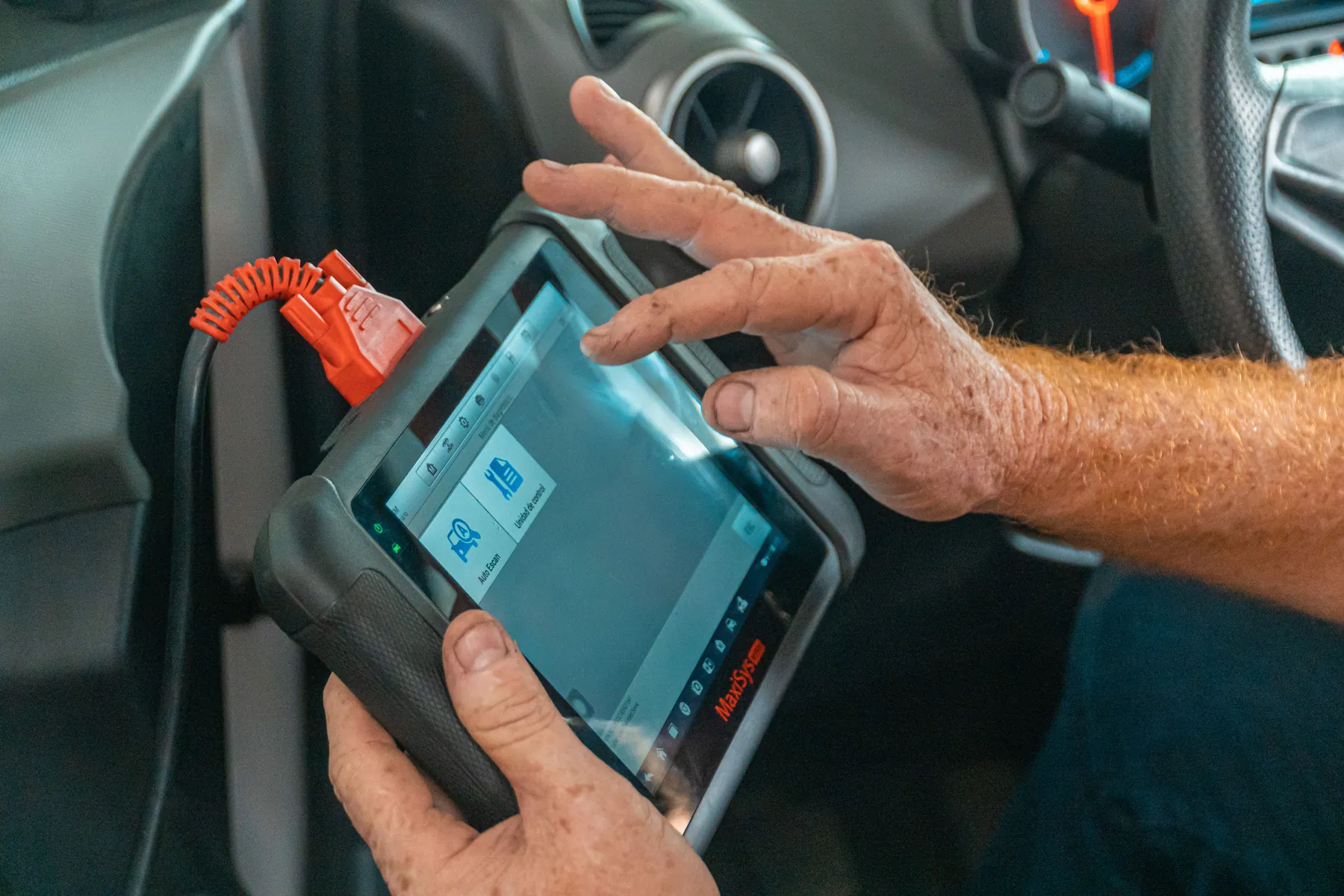 Araç içinde elektronik teşhis cihazını kullanan teknisyenin elleri